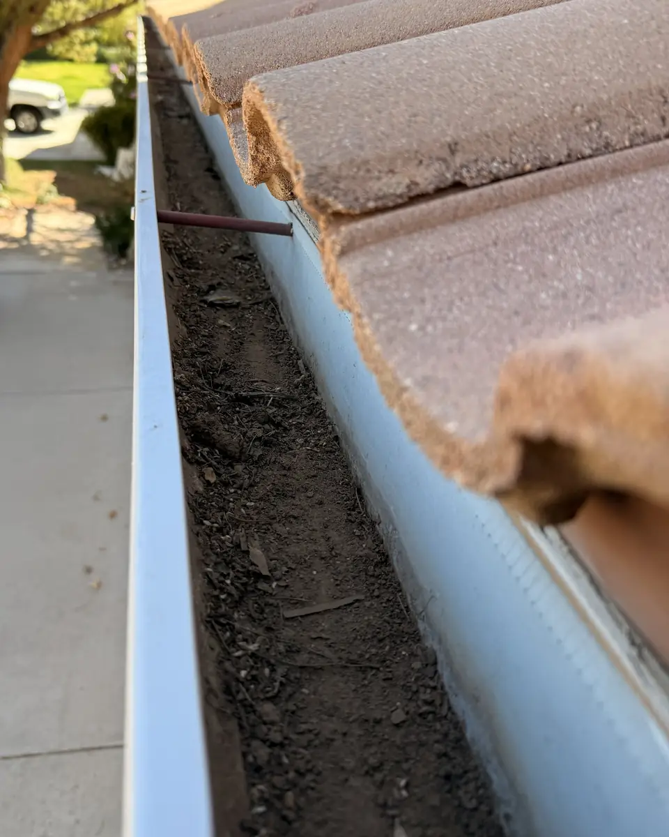 Before: Gutter packed with dirt, and the same gutter after cleaning