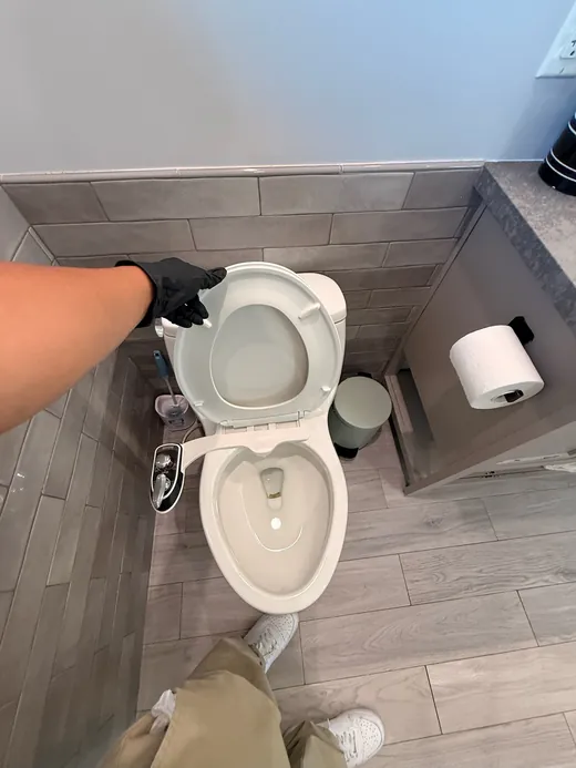 Toilet with a bidet attachment in a gray-tiled bathroom