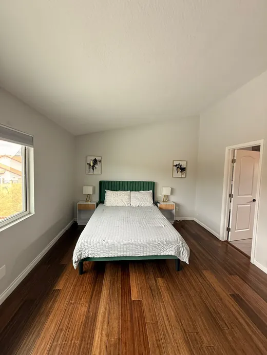Bedroom with a green headboard and dark hardwood floors
