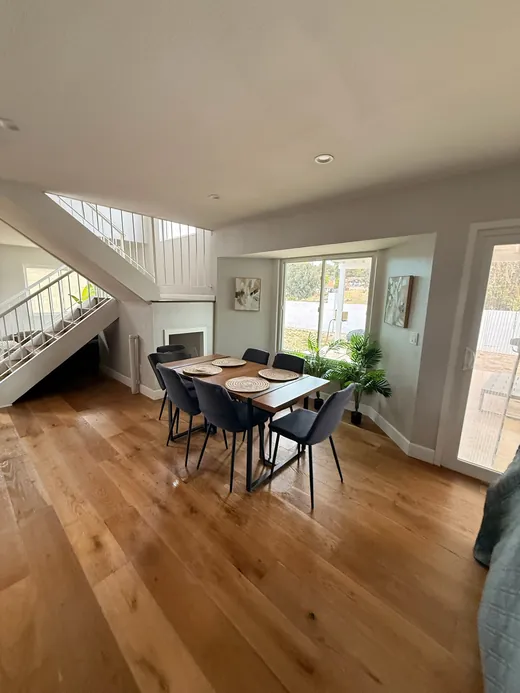 Dining area with a wood table, staircase and hardwood floors