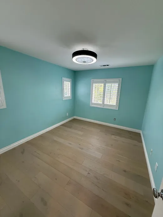 Empty bedroom with aqua walls and wood floors