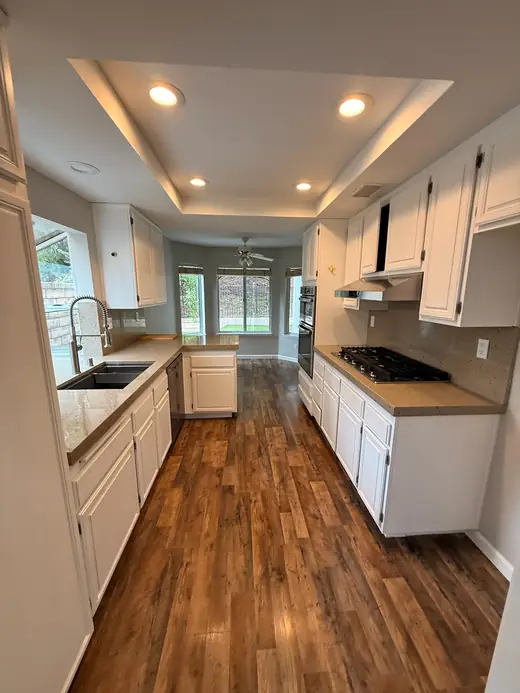 Empty kitchen with white cabinets and wood floors