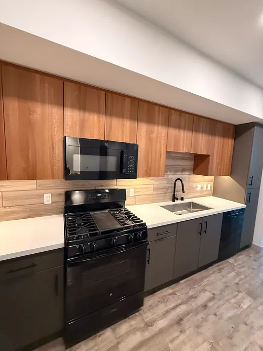 Empty kitchen with wood-grain cabinets and a black gas range