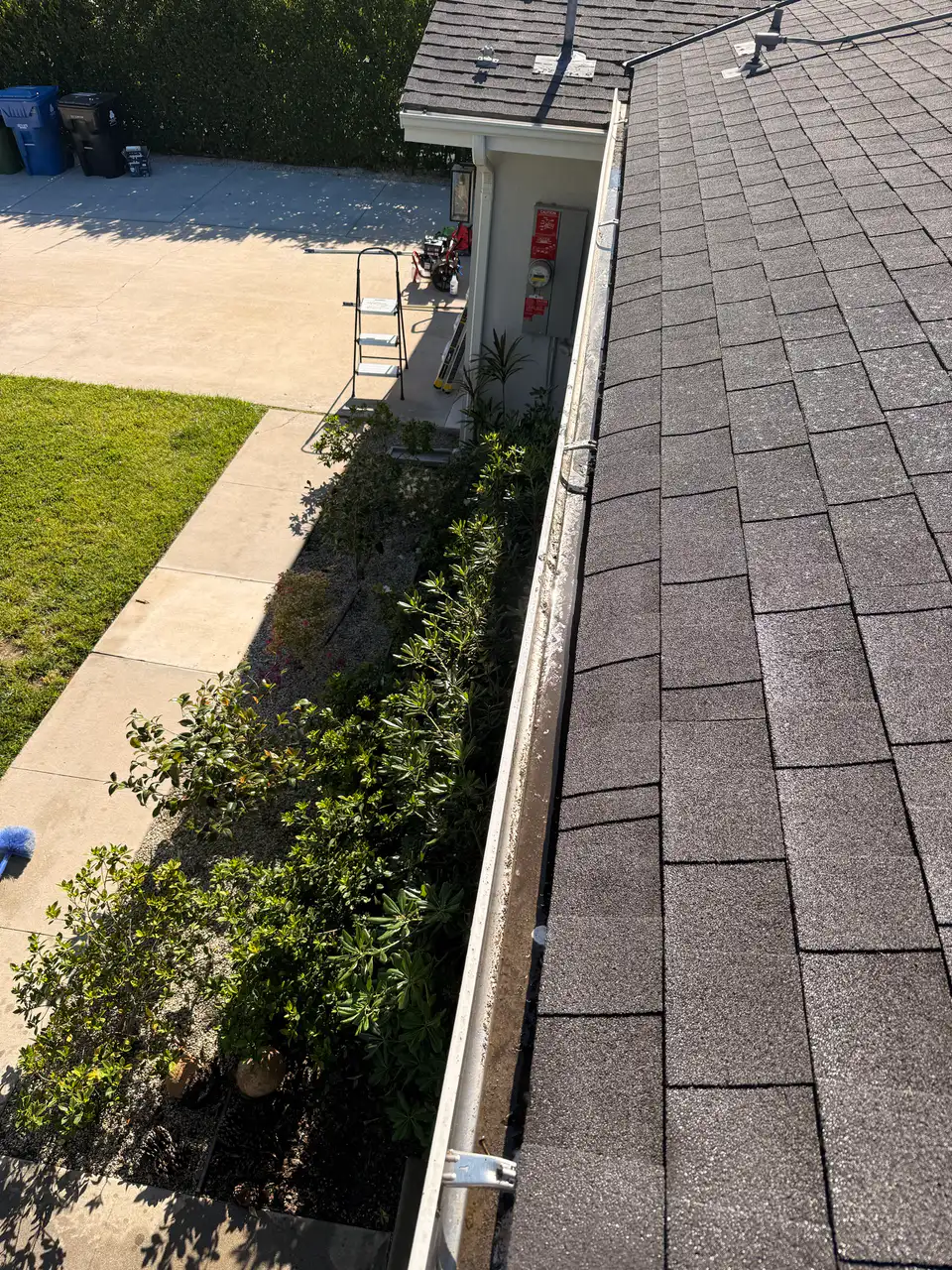 Long gutter run lined with grime and debris before cleaning