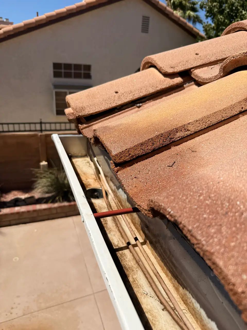 Tile-roof gutter lined with dirt and debris before cleaning
