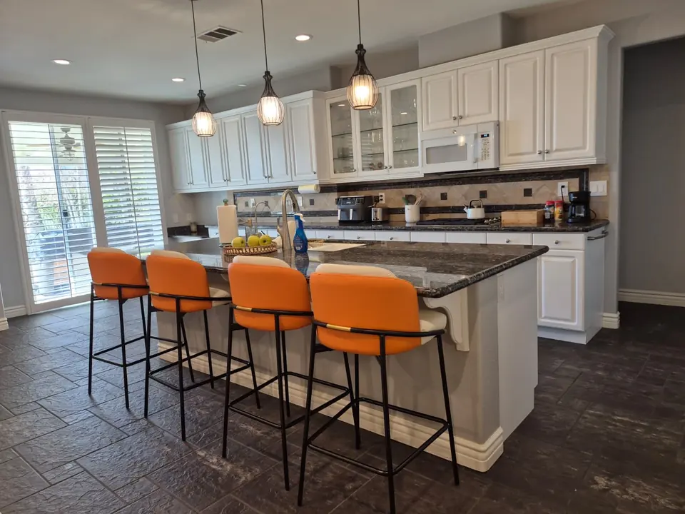 Bright kitchen with a granite island and orange stools