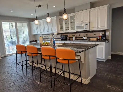 Bright kitchen with a granite island and orange stools
