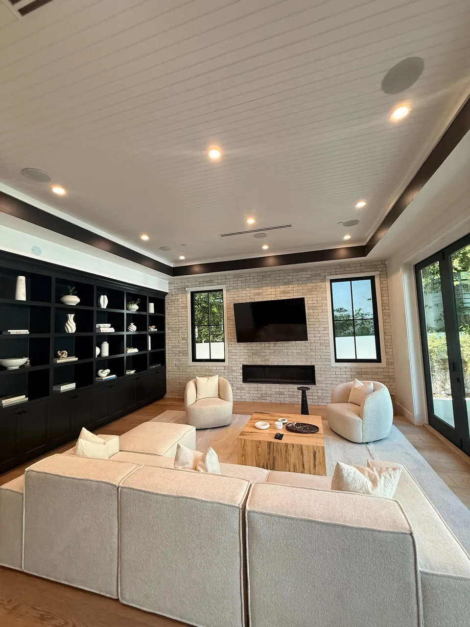 Living room with a shiplap ceiling, brick fireplace wall and built-in shelving