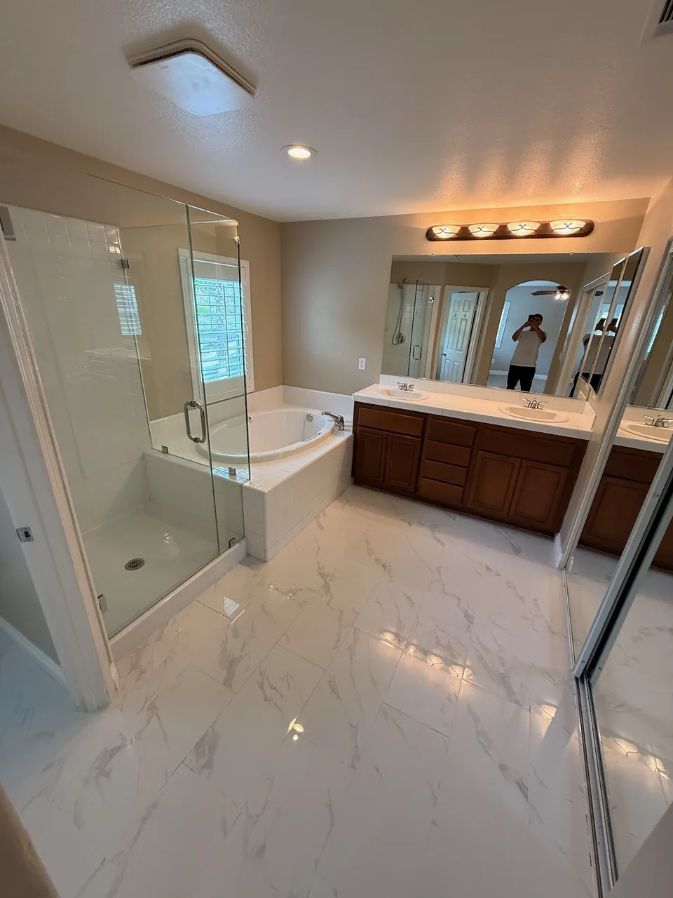 Primary bathroom with marble-look floors, soaking tub and glass shower