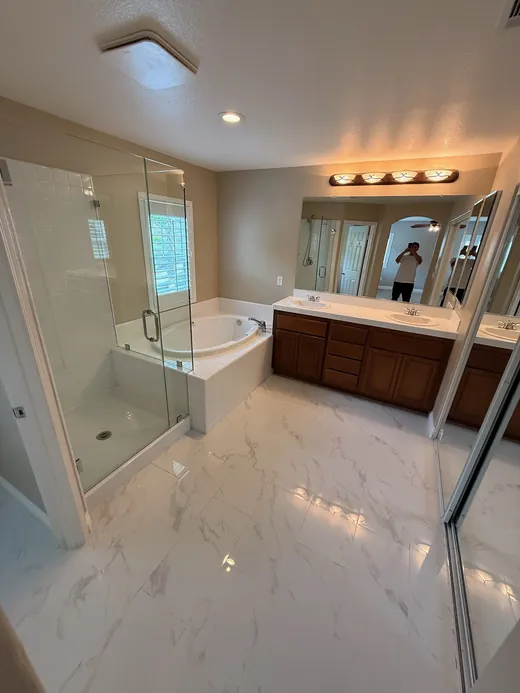 Primary bathroom with marble-look floors, soaking tub and glass shower