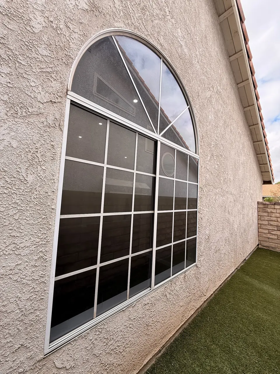 Large arched window on a stucco home