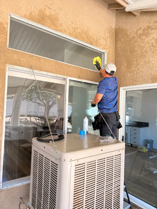 Team member wiping a high window on a stucco home
